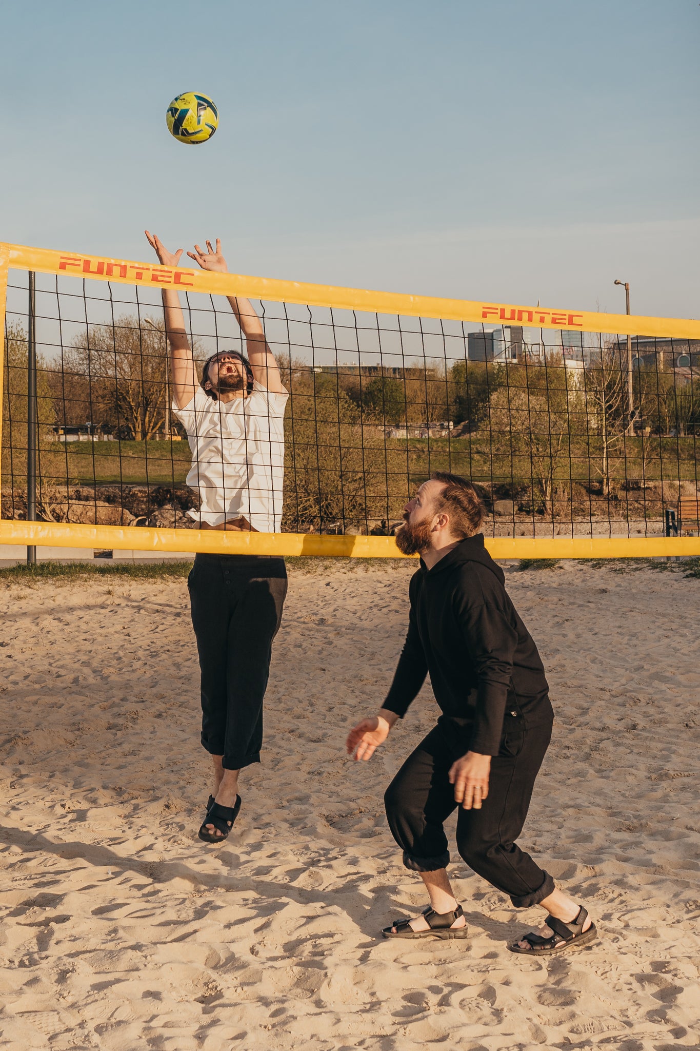 Brown leather sandals by Omaking, designed for comfort, featuring adjustable straps, worn on sandy beach during volleyball g