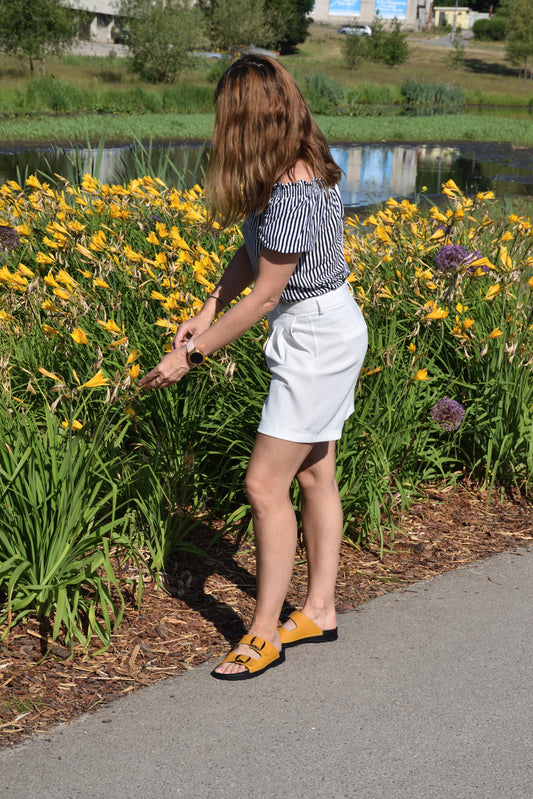 Ocre Meeliku sandals by Omaking, featuring a minimalist design and comfortable fit, worn with a white skirt.